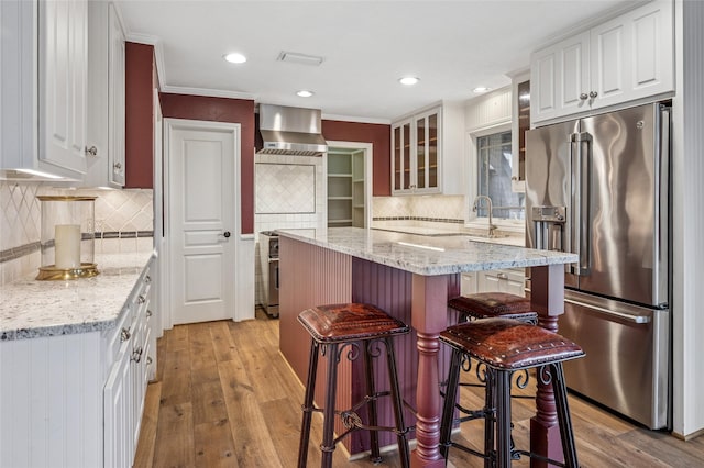 kitchen with a breakfast bar, high quality fridge, glass insert cabinets, and white cabinets