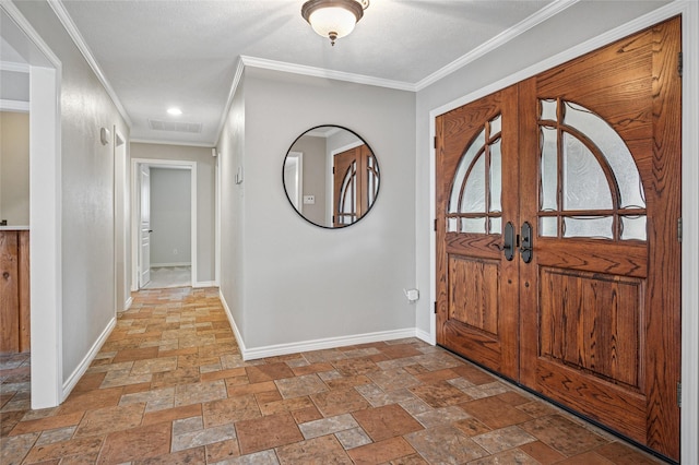 entryway featuring visible vents, ornamental molding, stone tile flooring, and baseboards