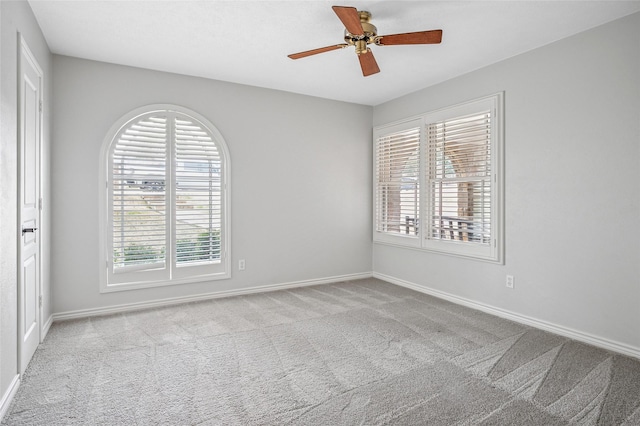 spare room with light carpet, ceiling fan, and baseboards