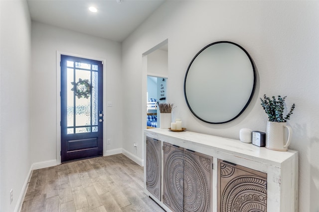 foyer with light wood-style flooring and baseboards