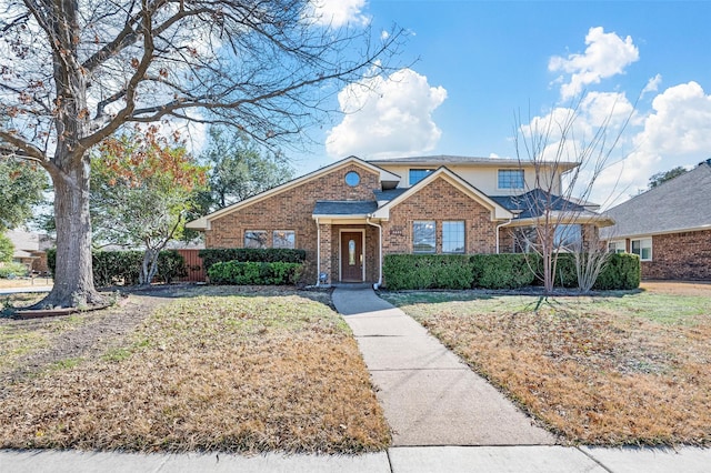 traditional-style home with fence, a front lawn, and brick siding