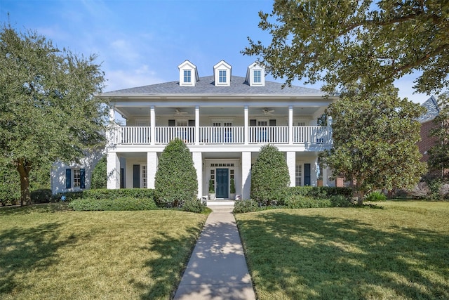 greek revival house featuring ceiling fan, a front yard, and a balcony