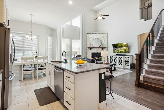 kitchen featuring decorative light fixtures, a center island with sink, stainless steel appliances, open floor plan, and a sink