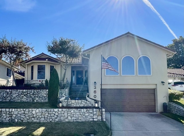 view of front of property with a garage, concrete driveway, and stucco siding