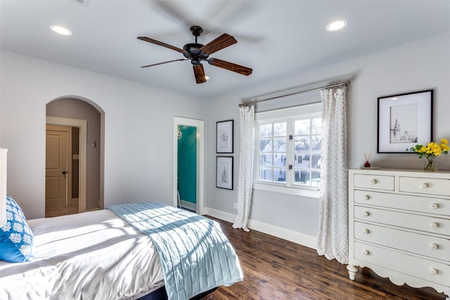 bedroom featuring baseboards, arched walkways, dark wood-type flooring, and recessed lighting