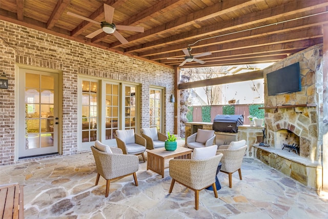 view of patio featuring ceiling fan, an outdoor stone fireplace, area for grilling, and fence