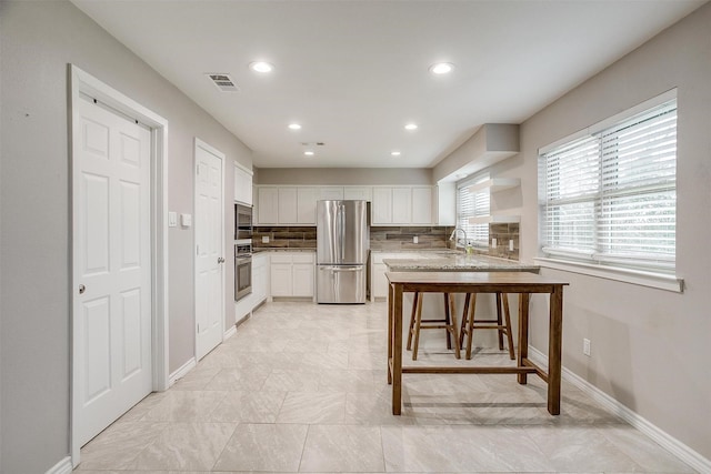 kitchen featuring tasteful backsplash, visible vents, appliances with stainless steel finishes, white cabinets, and a sink