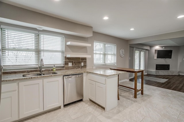 kitchen with dishwasher, a sink, white cabinetry, and light stone countertops