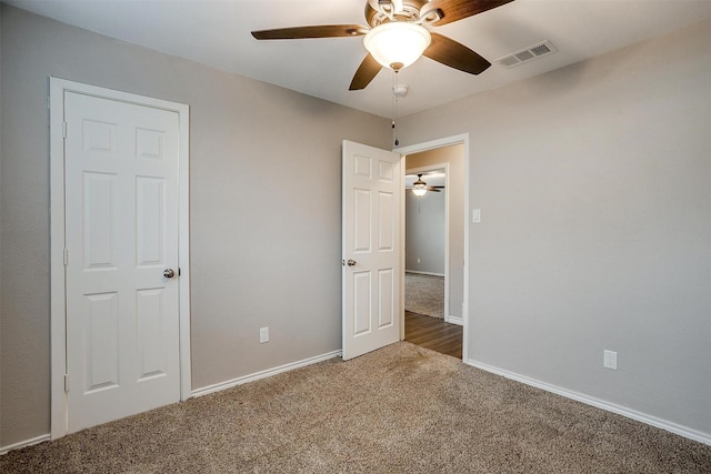 unfurnished bedroom featuring carpet floors, baseboards, visible vents, and ceiling fan