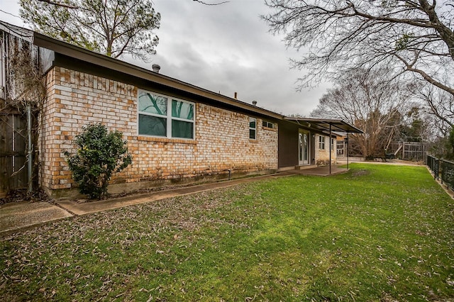 back of property featuring brick siding, a lawn, and fence