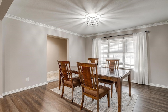 dining space with dark wood-type flooring, ornamental molding, and baseboards