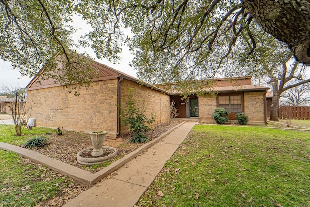 view of front of property featuring a front lawn, fence, and brick siding