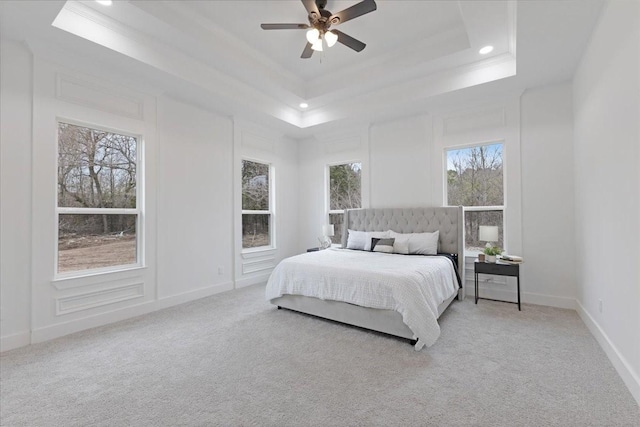 bedroom featuring light carpet, baseboards, a tray ceiling, and ornamental molding