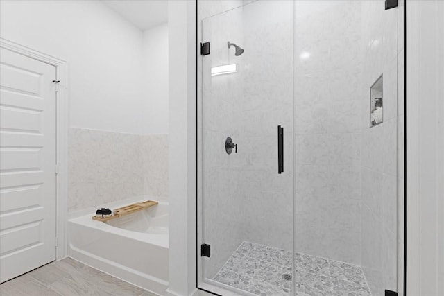 full bathroom featuring a shower stall and a bath