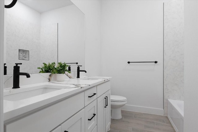 bathroom featuring double vanity, a sink, toilet, and baseboards