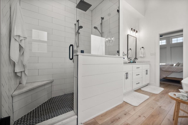 ensuite bathroom with ensuite bathroom, wood finished floors, vanity, and a shower stall