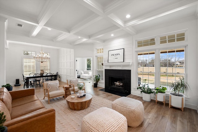 living room featuring a wealth of natural light, light wood finished floors, beam ceiling, and visible vents