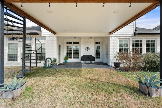 exterior space featuring a patio area, brick siding, stairway, and a lawn