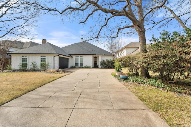 french provincial home with brick siding, a chimney, concrete driveway, an attached garage, and a front yard