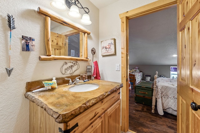 ensuite bathroom featuring a textured wall, vanity, ensuite bath, and wood finished floors