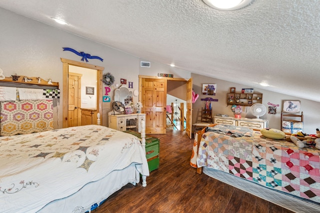 bedroom featuring dark wood-type flooring, lofted ceiling, visible vents, and a textured ceiling