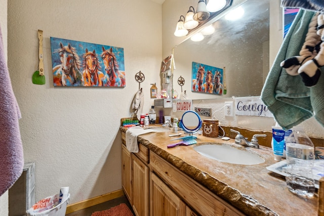 bathroom featuring a textured wall, vanity, and baseboards