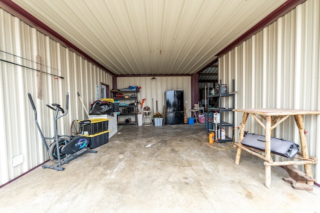 garage featuring metal wall and freestanding refrigerator