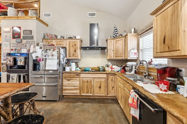 kitchen with a sink, wall chimney range hood, stainless steel fridge, and visible vents