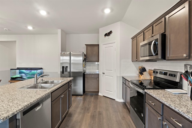 kitchen featuring decorative backsplash, light stone counters, appliances with stainless steel finishes, dark wood-type flooring, and a sink