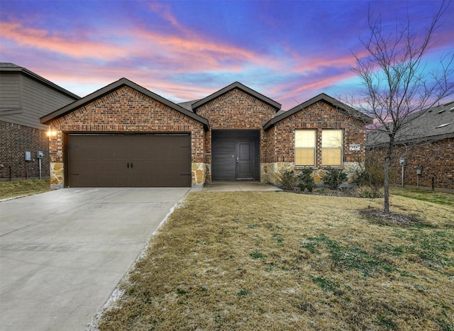 single story home featuring a garage, brick siding, driveway, and a lawn