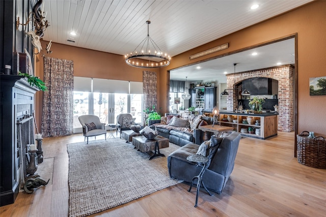 living room featuring light wood-style floors, a fireplace, and an inviting chandelier