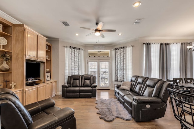 living area featuring light wood-style flooring, visible vents, crown molding, and french doors