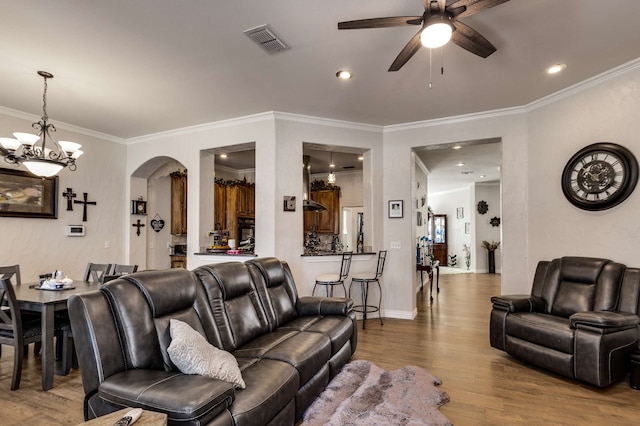 living area with ornamental molding, arched walkways, visible vents, and wood finished floors