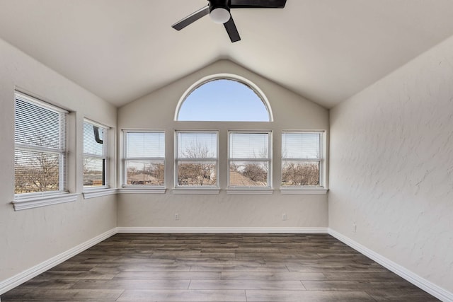 spare room with plenty of natural light, a ceiling fan, dark wood-type flooring, and a textured wall