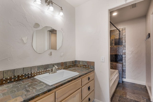 full bath with stone tile flooring, visible vents, vanity, shower / tub combination, and baseboards