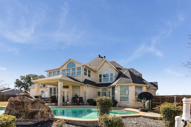 back of property featuring a fenced in pool, stone siding, a patio area, and fence