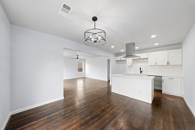 kitchen featuring visible vents, island range hood, light countertops, white cabinetry, and pendant lighting