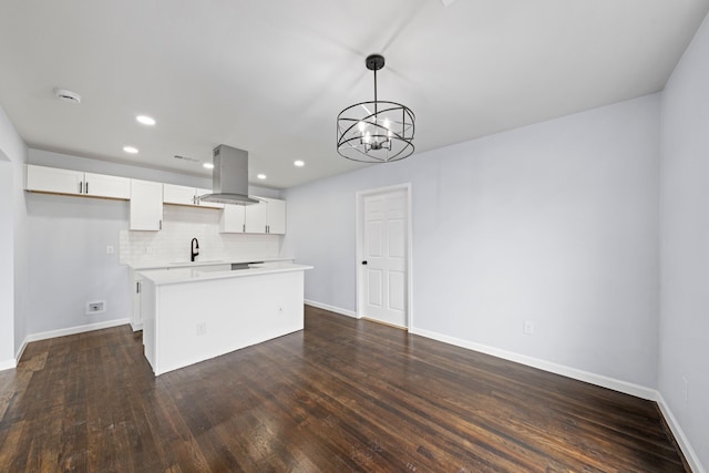 kitchen with a center island, hanging light fixtures, island exhaust hood, light countertops, and white cabinetry