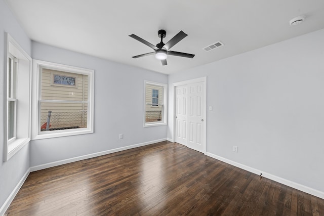 spare room with baseboards, visible vents, ceiling fan, and dark wood-style flooring