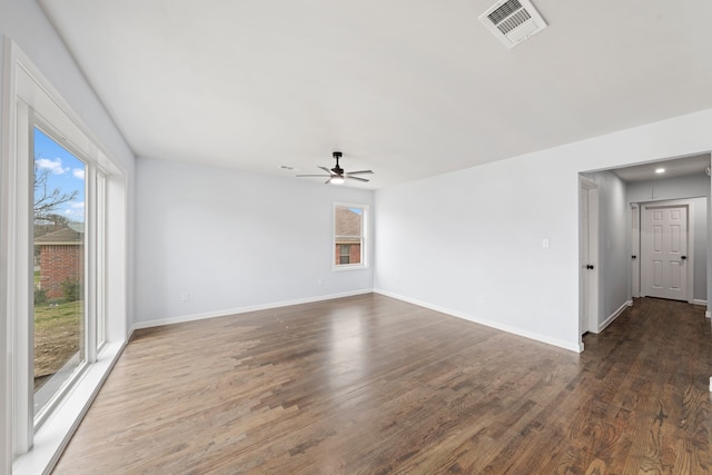 empty room featuring dark wood-style floors, baseboards, visible vents, and ceiling fan