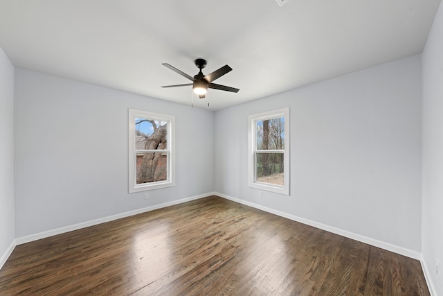 unfurnished room with baseboards, dark wood finished floors, and a wealth of natural light