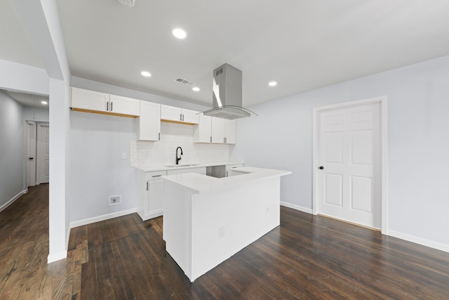 kitchen with light countertops, visible vents, white cabinets, a sink, and island range hood