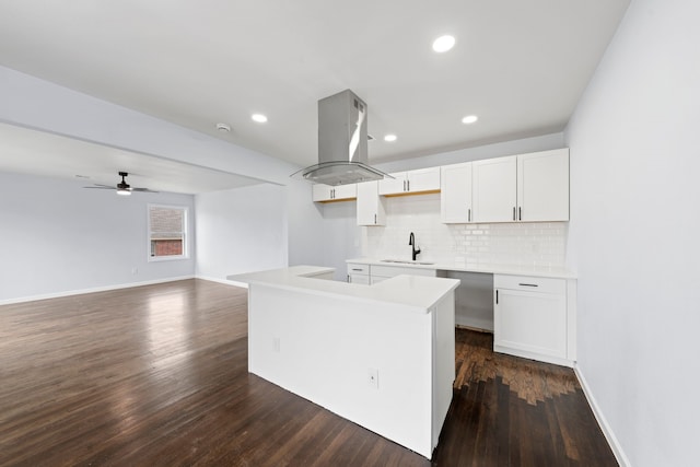 kitchen featuring a center island, island exhaust hood, light countertops, white cabinetry, and a sink