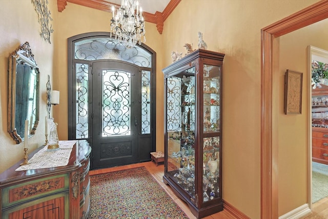 entrance foyer featuring ornamental molding, wood finished floors, and an inviting chandelier