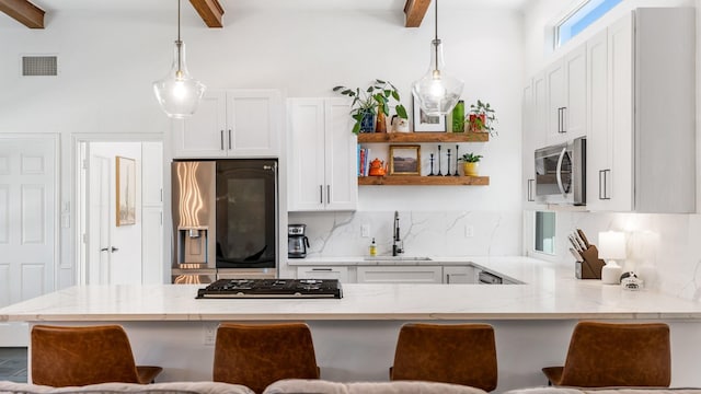 kitchen with a peninsula, appliances with stainless steel finishes, a sink, and a kitchen breakfast bar