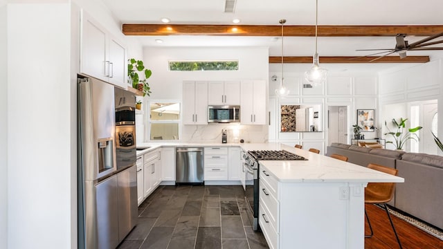 kitchen featuring white cabinetry, a kitchen bar, appliances with stainless steel finishes, and open floor plan