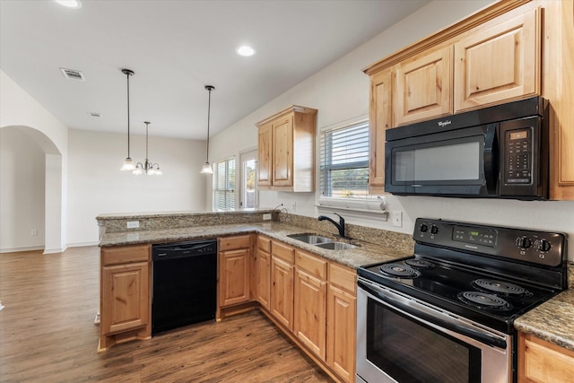 kitchen featuring a peninsula, a sink, visible vents, black appliances, and decorative light fixtures