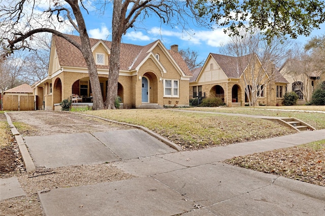 view of front facade with a front yard, brick siding, driveway, and a chimney