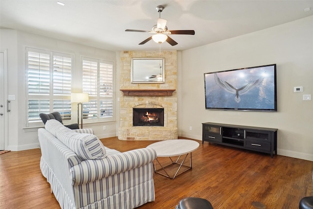 living room with a ceiling fan, a fireplace, baseboards, and wood finished floors