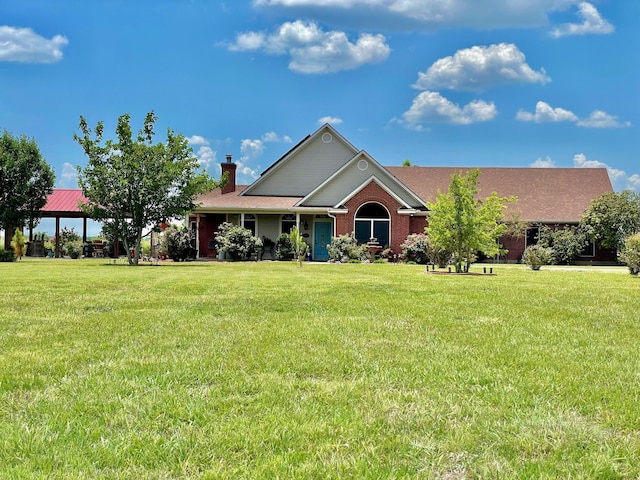 view of front of property featuring brick siding, a chimney, and a front yard